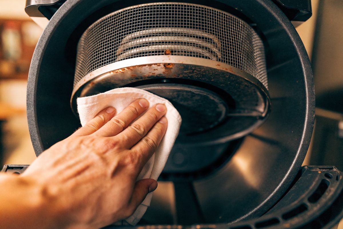 Ferrugem na resistência da parte de cima da air fryer sendo limpa com pano seco